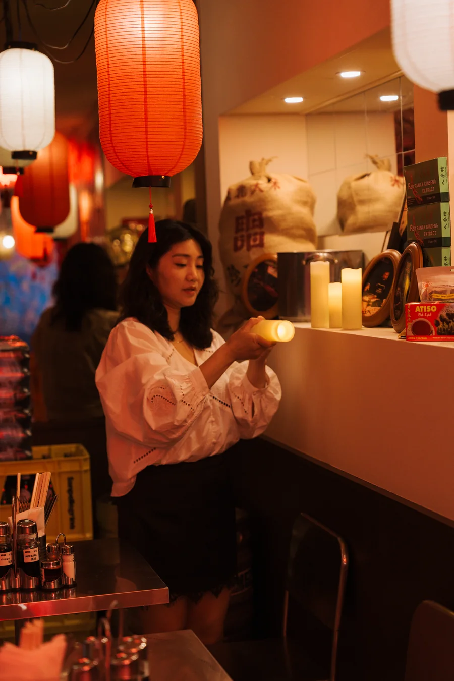 Une personne assise au comptoir sous une lanterne rouge