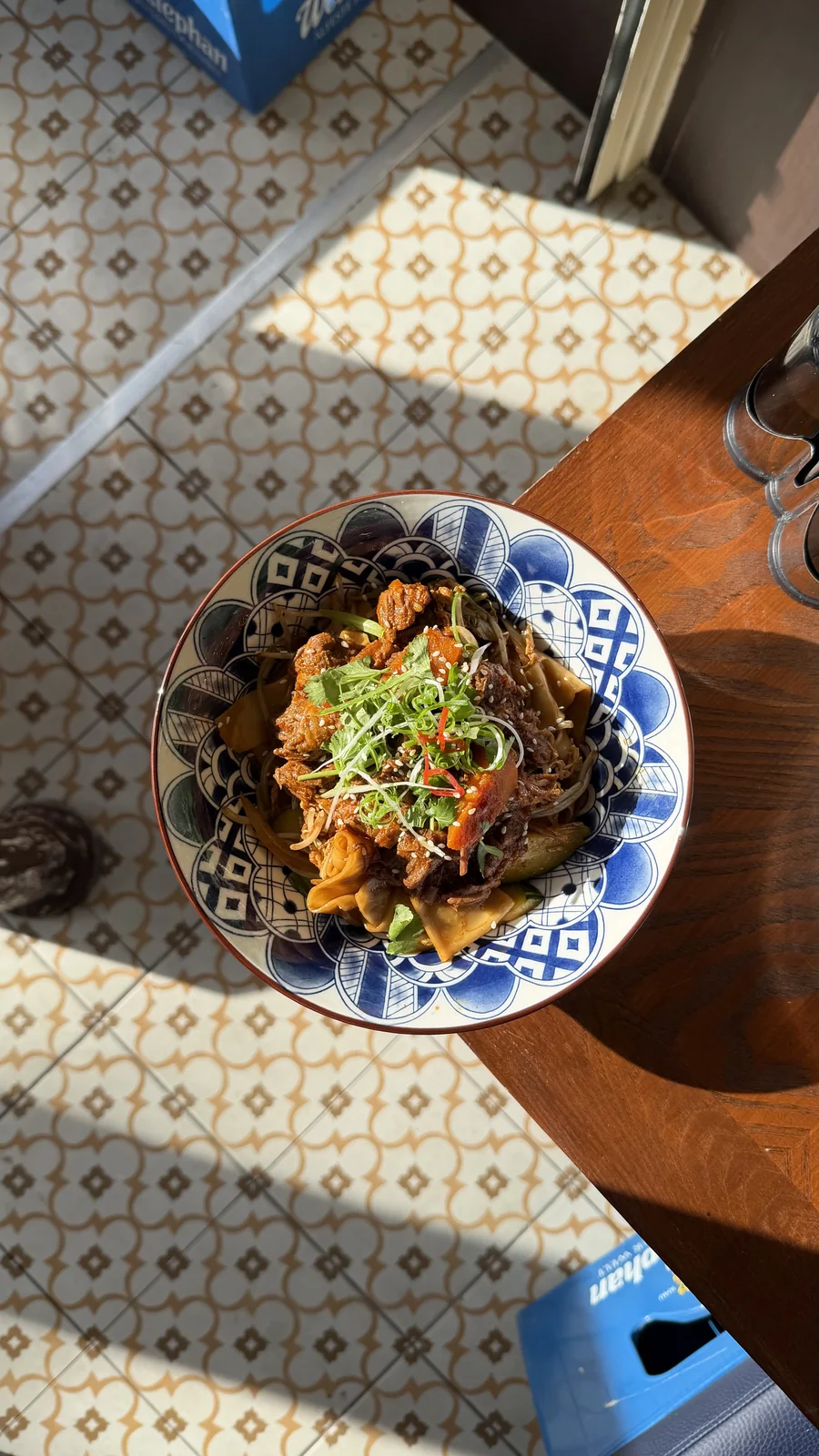 Bol de nouilles sur une table de MIYAN, avec le carrelage éclairé par le soleil